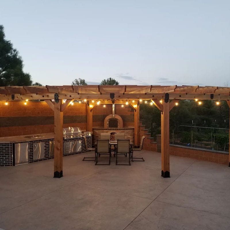 Outdoor Kitchen under a Pergola with a Rustic Brick Pizza Oven centerpiece