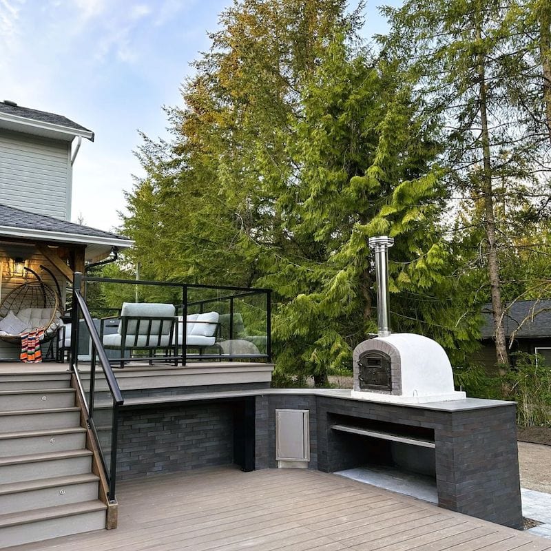 Lume Alto Premium Oven set on a black outdoor kitchen countertop next to the seating area