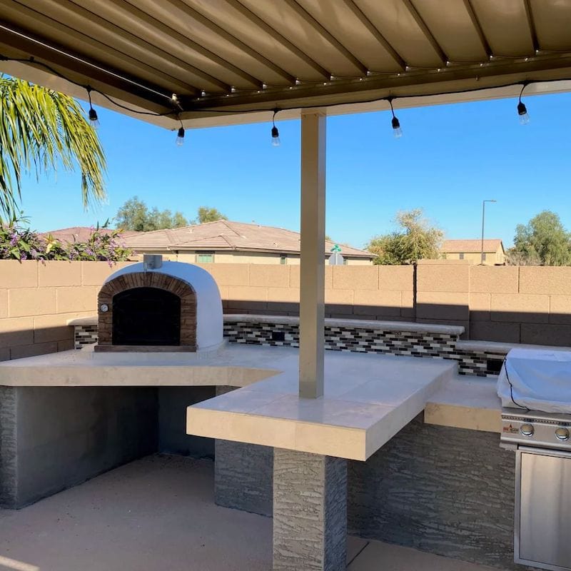 Ventura Sierra Brick Oven set on an outdoor kitchen counter under a pergola