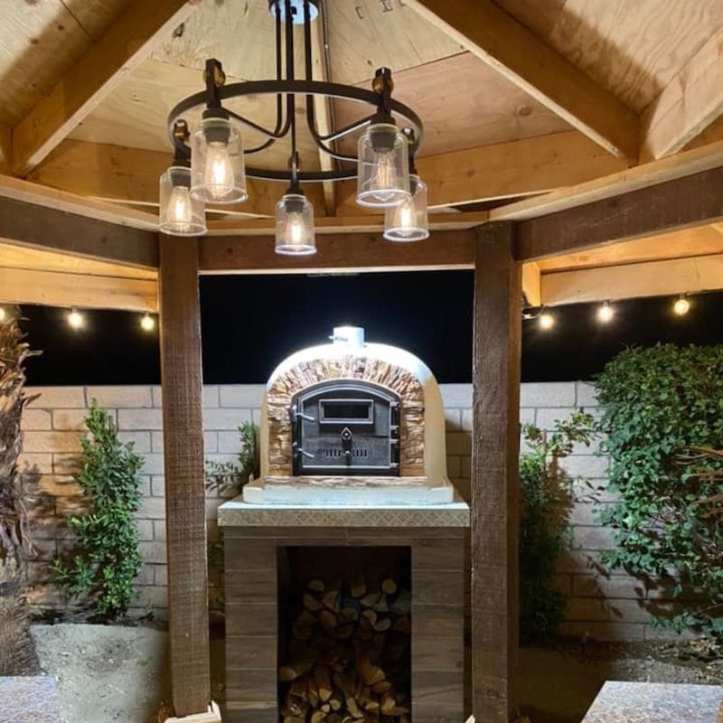 Ventura Sierra Brick Oven set on an outdoor kitchen counter under a pergola with light setting surround